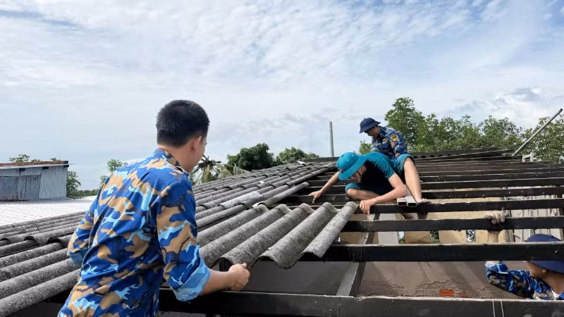 Cán bộ, chiến sĩ Lữ đoàn 175 cùng các lực lượng tháo dỡ phần mái nhà bị hư hỏng do dông lốc. (Ảnh: Vùng 5 Hải quân cung cấp)