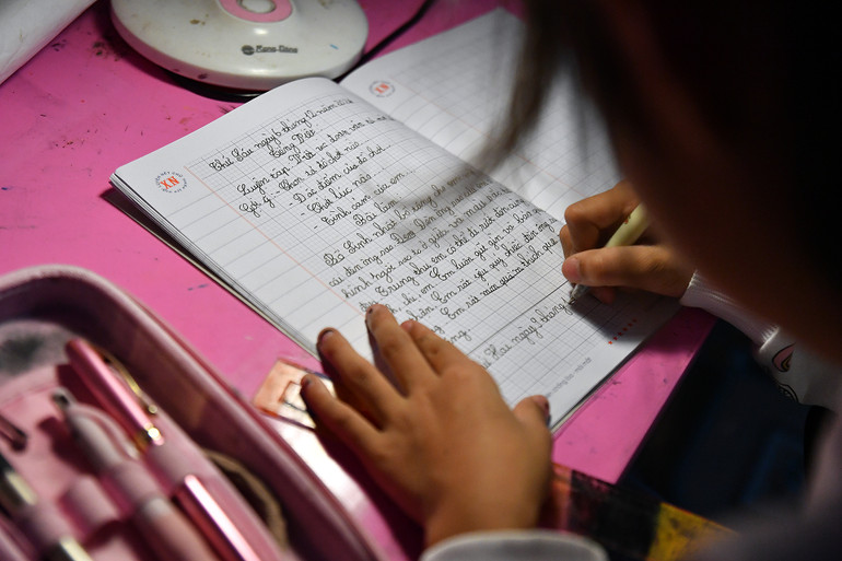 Bố của Nhã Linh từng bị tai nạn gây chấn thương sọ não, suy giảm khả năng lao động. 2 năm trước, bố mẹ cô bé ly hôn. Từ đó, em sống với ông bà nội và bố. Trong ảnh: Nhã Linh làm bài tập viết 1 đoạn văn tả về bố.