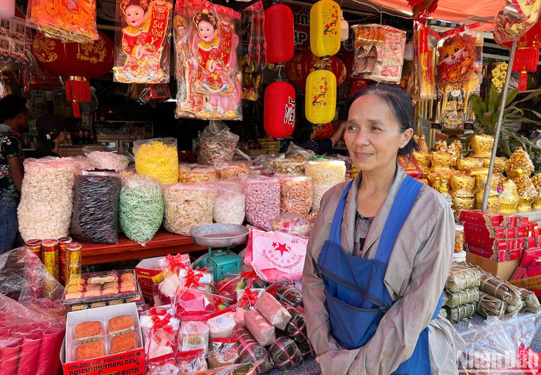 Chị Bé Chòi bên quầy kinh doanh của gia đình bán bánh, mứt, kẹo và lịch Việt Nam. (Ảnh: TRỊNH DŨNG)