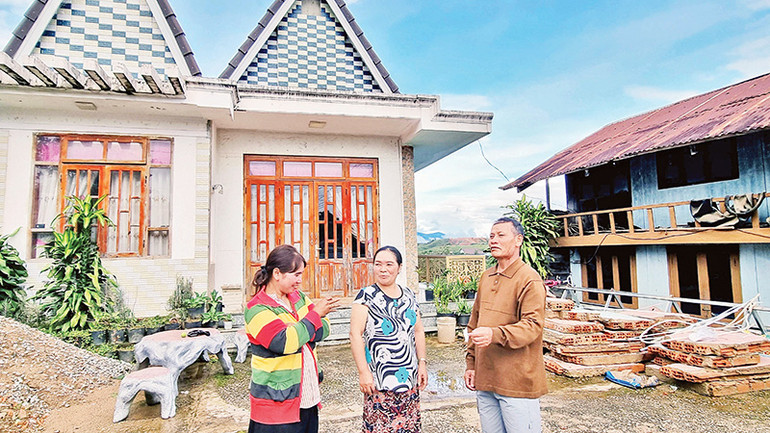 Vợ chồng ông Ha Tin và con dâu-trưởng thôn Liêng Bông trước ngôi nhà của Ha Tin vừa tháo dỡ hàng rào để hiến đất làm đường liên thôn.