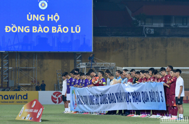 Các cầu thủ và khán giả tại sân Hàng Đẫy dành phút mặc niệm tới những người đã mất do ảnh hưởng của bão số 3 vừa qua. (Ảnh: TRẦN HẢI)