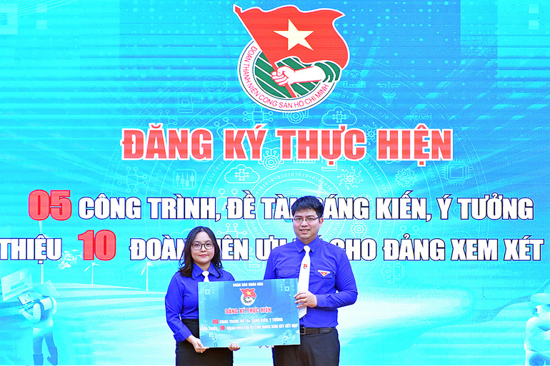 Bí thư Đoàn Thanh niên Báo Nhân Dân Lê Khánh Bình (bên trái) trao biển đăng ký thực hiện các công trình thanh niên hưởng ứng đợt thi đua.