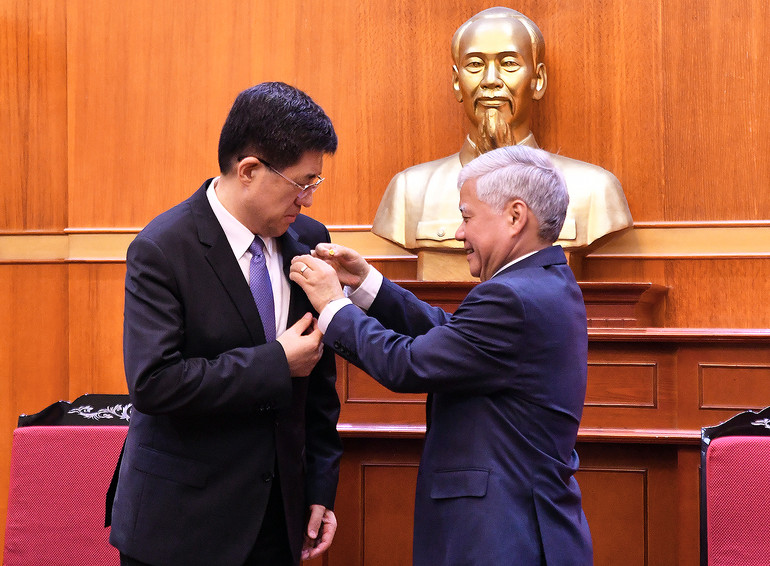 Đồng chí Đỗ Văn Chiến gắn huy hiệu Mặt trận Tổ quốc Việt Nam tặng Bí thư thứ nhất Ban Bí thư Trung ương Đoàn Thanh niên Cộng sản Trung Quốc A Đông.