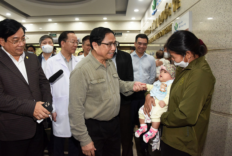 Thủ tướng hỏi thăm sức khỏe một trẻ đang khám tại Bệnh viện Nhi Trung ương trong thời điểm thời tiết chuyển mùa.