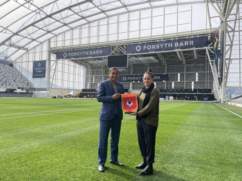 Huấn luyện viên Mai Đức Chung trao cờ lưu niệm cho đại diện sân vận động Dunedin (Yorsyth Barr). (Ảnh: VFF)