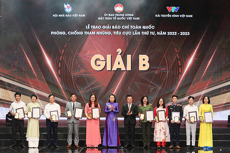 Tổng Biên tập Báo Nhân Dân, Phó Trưởng Ban Tuyên giáo Trung ương Lê Quốc Minh và Phó Chủ tịch, Tổng Thư ký Ủy ban Trung ương Mặt trận Tổ quốc Việt Nam Nguyễn Thị Thu Hà (thứ 6 và 7 từ phải sang) trao chứng nhận tặng đại diện các tác giả, nhóm tác giả giành giải B.