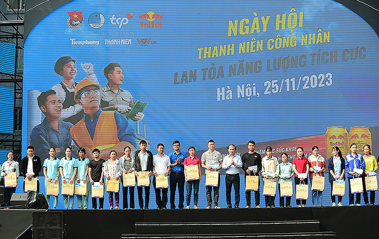 Các đồng chí Phạm Tất Thắng, Ủy viên Trung ương Đảng, Phó Trưởng Ban Thường trực Ban Dân vận Trung ương; Bùi Quang Huy, Ủy viên dự khuyết Trung ương Đảng, Bí thư thứ nhất Trung ương Đoàn (thứ 9 và 12 từ phải sang) trao quà tặng thanh niên công nhân.