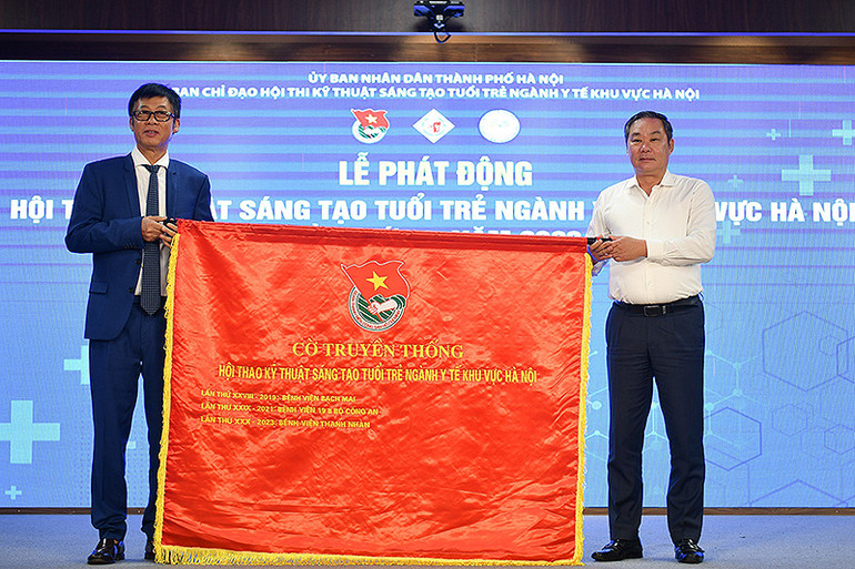 Phó Chủ tịch Ủy ban nhân dân thành phố Hà Nội Lê Hồng Sơn (bên phải) trao cờ truyền thống của Hội thi cho PGS, TS Đào Quang Minh, Giám đốc Bệnh viện Thanh Nhàn - đơn vị đăng cai Hội thi năm nay.