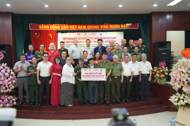 Thân nhân liệt sĩ tiếp nhận hồ sơ Chứng tích Chiến tranh liên quan liệt sĩ của gia đình.