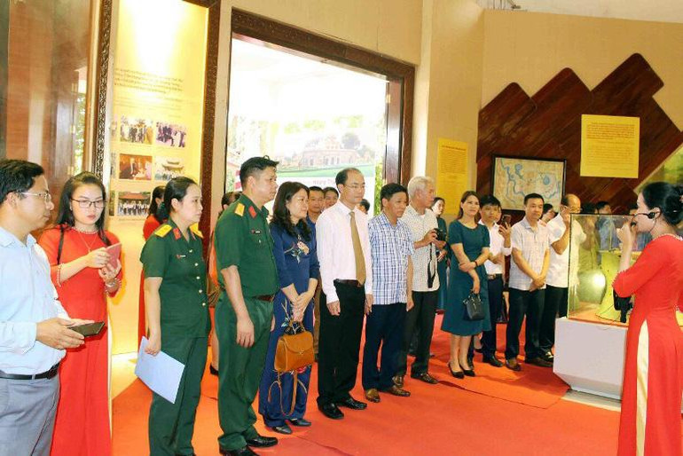 Các đại biểu, khách tham quan nghe giới thiệu về các hiện vật trưng bày.