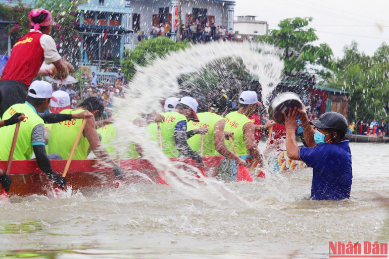 Vận động viên vục mạnh mái dầm xuống nước để đưa thuyền mình vượt lên.