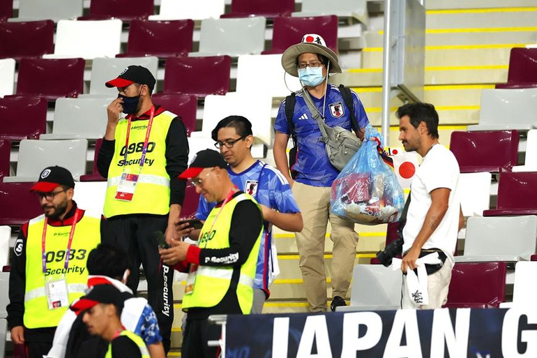 Một cổ động viên Nhật Bản hỗ trợ nhân viên của nước chủ nhà Qatar dọn rác trên khán đài. (Ảnh: B/R Football)