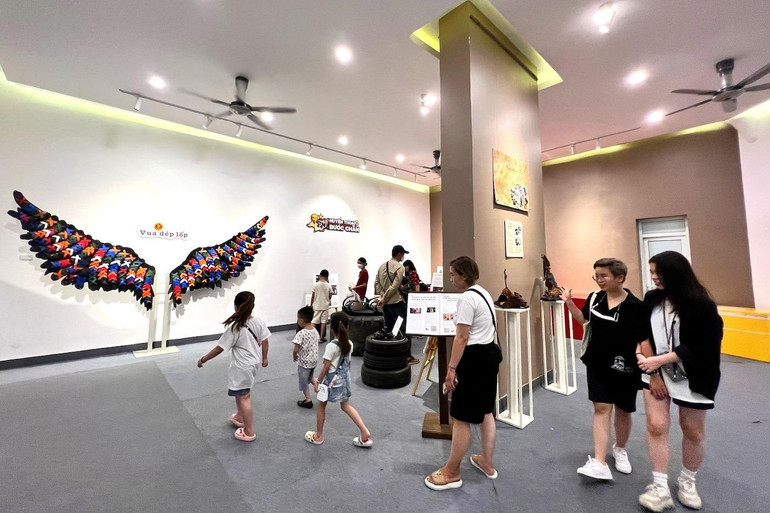 Nhiều em nhỏ thích thú khi được phụ huynh dẫn tham quan, chụp ảnh đồng thời giải thích, kể chuyện lịch sử dép lốp.