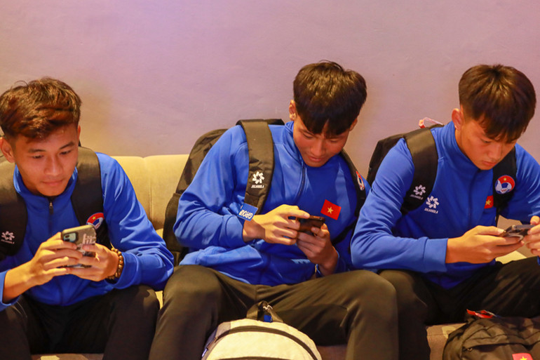 Các cầu thủ tranh thủ nhắn tin cho gia đình và người thân trong lúc chờ đợi cán bộ đoàn làm thủ tục check-in khách sạn.