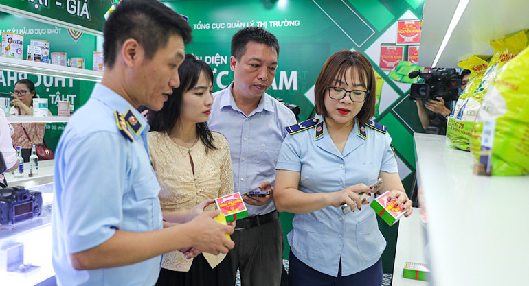 Chuyên viên của Tổng cục Quản lý thị trường hướng dẫn khách tham quan nhận diện bánh cốm Nguyên Ninh thật-giả.