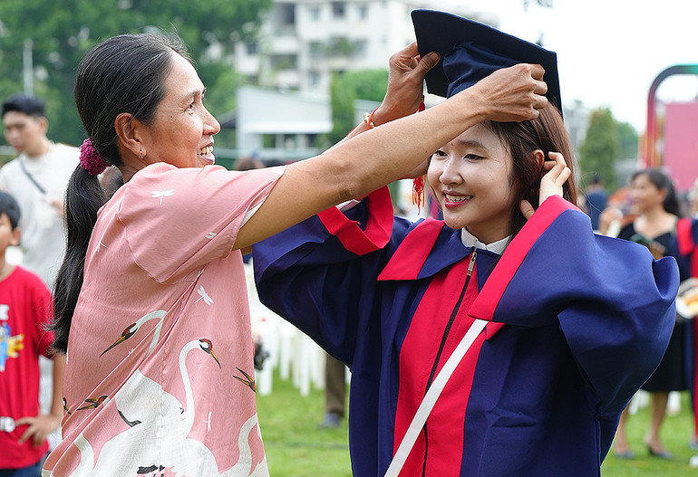 Một nữ sinh được mẹ đội cho chiếc mũ cử nhân.
