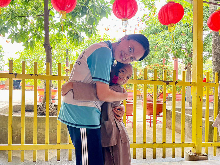 Minh Anh chụp ảnh lưu niệm với 1 em nhỏ trong chuyến thiện nguyện tại chùa Từ Hạnh (quận Bình Tân) cùng bạn bè Trường Phổ thông Năng khiếu. Ảnh: Nhân vật cung cấp
