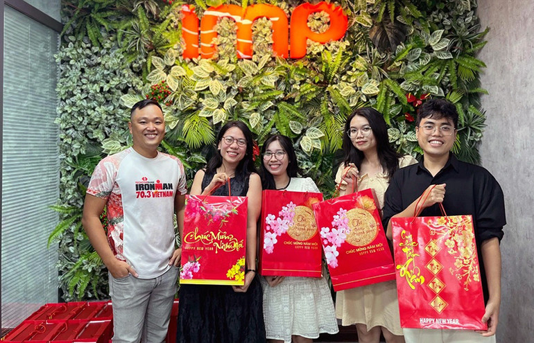 Võ Minh Quân (ngoài cùng bên trái) trao quà Tết tặng các cộng sự tại công ty.