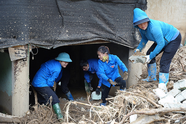 Các nữ tình nguyện viên trong màu áo xanh tích cực dọn dẹp đống đổ nát.