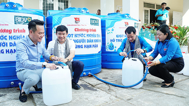 Các đồng chí đại diện Trung ương Đoàn, Hội Doanh nhân trẻ Việt Nam và các đơn vị liên quan lấy nước sạch vào can để trao tặng người dân địa phương.