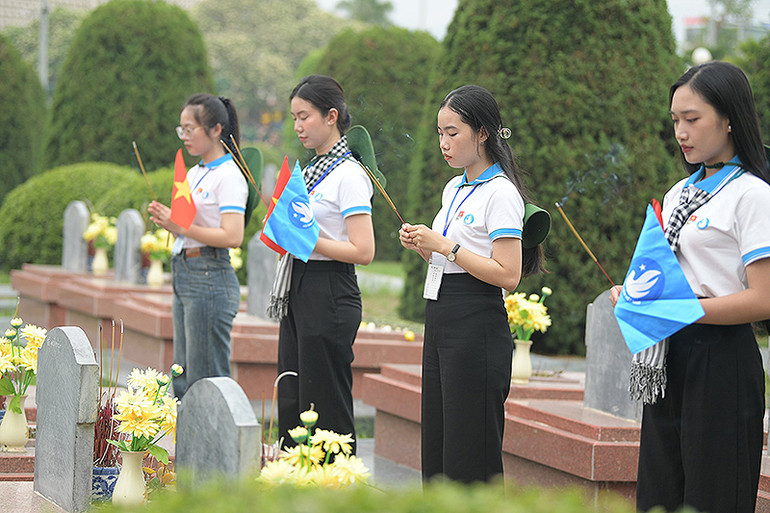 Các đại biểu thành kính dâng hương tại mộ liệt sĩ trong khuôn viên nghĩa trang.