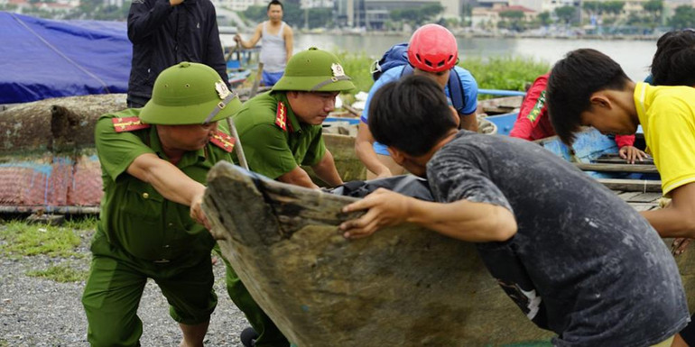 Công an phường Thuận Phước hỗ trợ ngư dân di dời tàu cá lên bờ.
