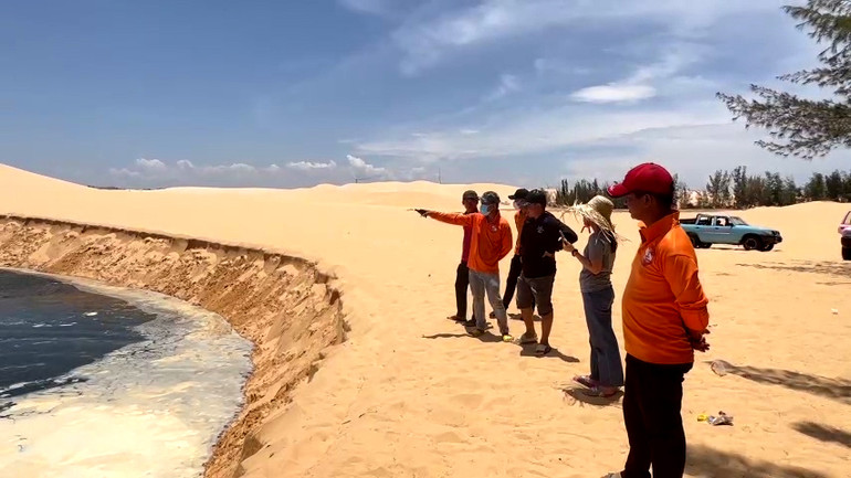 Người dân và du khách theo dõi hiện tượng sạt lở cát tại điểm du lịch Bàu Trắng.