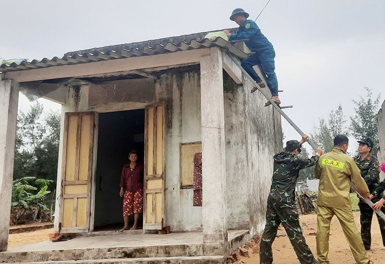 Lực lượng vũ trang giúp người dân ở ven biển huyện Thăng Bình chằng chống nhà cửa.
