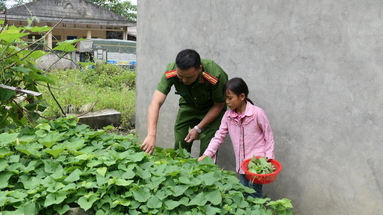 Cháu Vù Thị Sinh hái rau xanh cùng cán bộ Công an xã Nghĩa Thuận, huyện Quản Bạ.