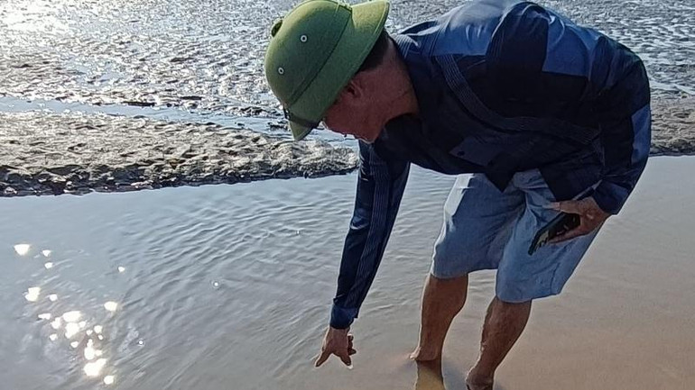 Người dân chỉ cho phóng viên xem vệt dầu loang còn đọng trên vũng nước nuôi ngao xã Thái Đô (huyện Thái Thụy, tỉnh Thái Bình).