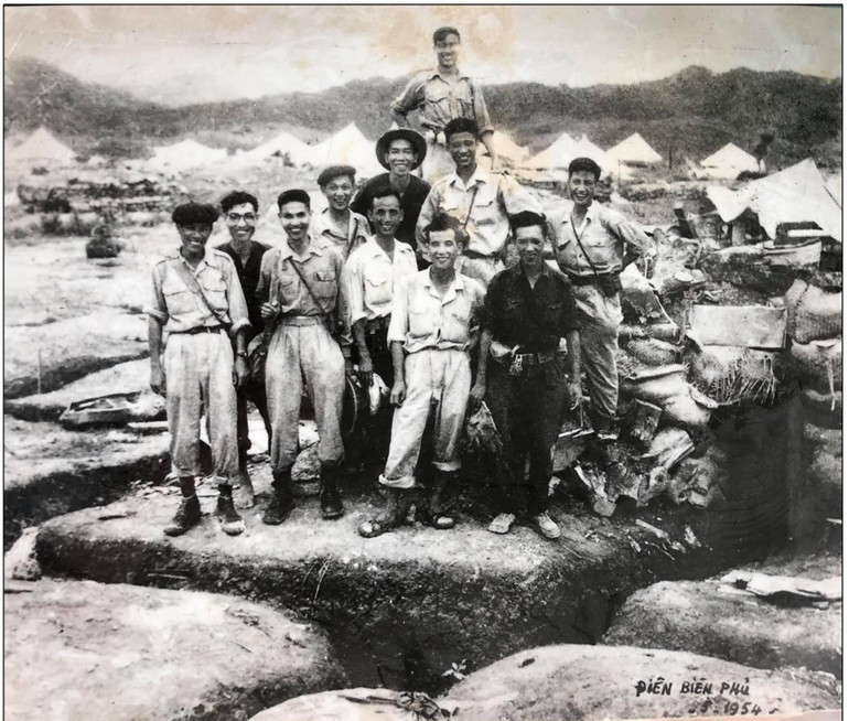 Đoàn làm phim tài liệu và nhiếp ảnh tham gia Chiến dịch Điện Biên Phủ - Những người chép sử Điện Biên bằng hình ảnh. Ảnh chụp ngày 8/5/1954. (Nguồn: Cục Điện ảnh). Từ trái sang: Hàng đầu: 1. Quay phim chính, Đạo diễn Nguyễn Tiến Lợi; 2. Quay phim Nguyễn Đăng Bảy; 3. Quay phim Nguyễn Phụ Cấn; 4. Quay phim Nguyễn Như Ái; 5. Quay phim Nguyễn Ngọc Quỳnh. Hàng thứ hai: 1. Quay phim Nguyễn Hồng Nghi; 2. Quay phim Nguyễn Thụ; 3. Quay phim Phan Trọng Quỳ; 4. Nhiếp ảnh Triệu Đại; 5. Nhiếp ảnh Đinh Ngọc Thông. Hàng thứ ba: Ông Nguyễn Sinh, người dân tộc giúp đoàn mang vác dụng cụ.