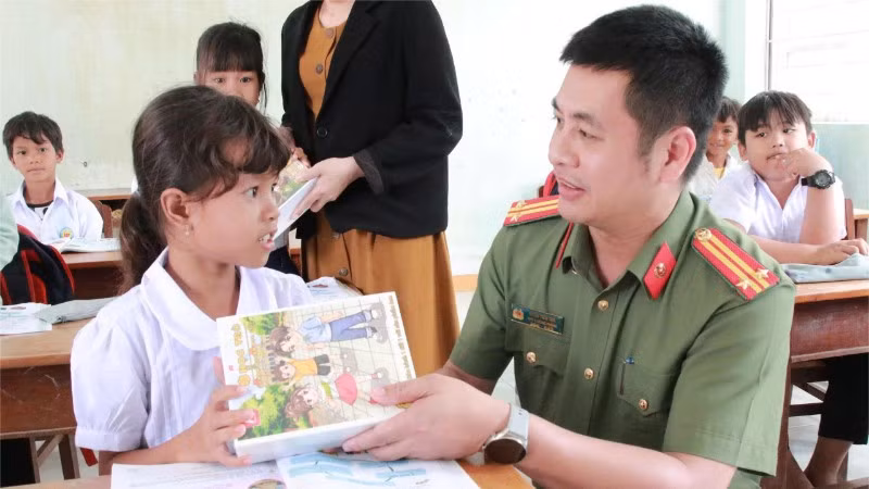 Cán bộ Công an tỉnh Đắk Lắk trao tặng sách vở cho học sinh vùng lũ tại xã Phú Mỡ sau khi các em trở lại trường học.