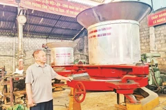 Bác Vũ Hữu Lê bên sản phẩm máy vò chè đa năng.