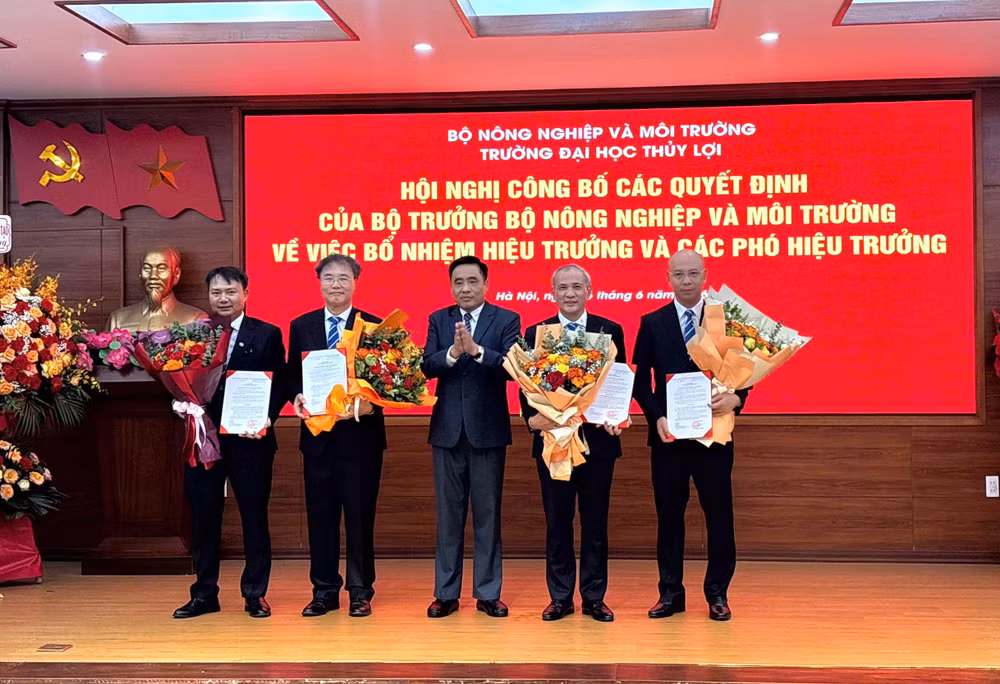 Thứ trưởng Nông nghiệp và Môi trường Nguyễn Quốc Trị trao quyết định và tặng hoa cho Ban giám hiệu Trường đại học Thủy lợi. 