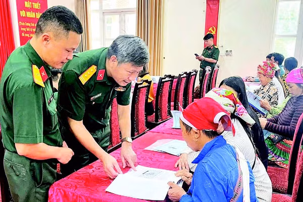 Cán bộ Đoàn Kinh tế-Quốc phòng 345 trao đổi, hướng dẫn người dân kỹ thuật chăn nuôi. (Ảnh QUANG PHẤN)