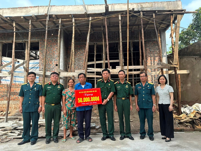 Cựu chiến binh Phạm Văn Lượng (đứng giữa) nhận hỗ trợ xây nhà mới. (Ảnh NGỌC LAN)