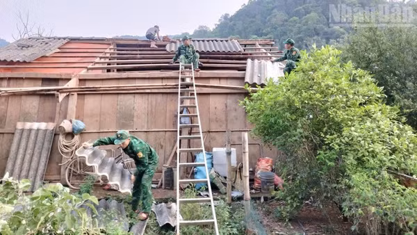 Cán bộ, chiến sĩ Đồn Biên phòng Chiềng Sơn giúp hộ gia đình anh Lò Văn Thực lợp lại mái nhà. (Ảnh: QUÀNG HÙNG)