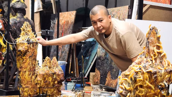 Lê Hữu Hiếu trong quá trình chuẩn bị cho tác phẩm. Anh cho tằm nhả tơ dệt trực tiếp trên bề mặt tác phẩm. (Ảnh: NVCC)