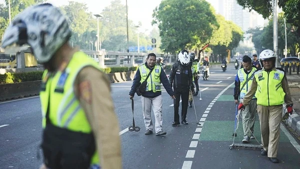 Các tình nguyện viên thu gom đinh trên đường phố Jakarta. Ảnh: AP