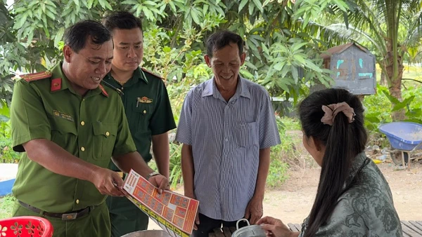 Trung tá Châu Văn Nát phát tờ rơi tuyên truyền cho người dân các phương thức tội phạm mới để nâng cao cảnh giác.