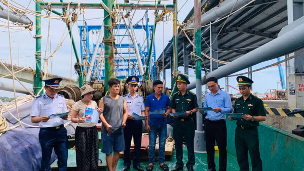 Các đơn vị tuyên truyền, phát tờ rơi trên các tàu cá đang neo đậu tại Cảng Nam Cửa Việt. (Ảnh: XUÂN THẾ).