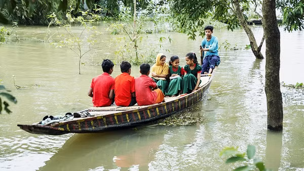 Trẻ em Bangladesh chèo thuyền qua vùng ngập lụt để đến trường. Ảnh: UNICEF