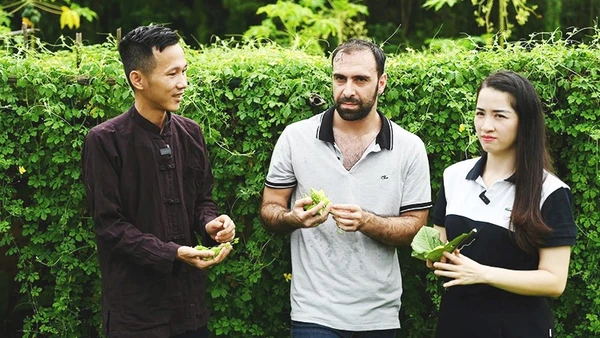 Anh Hoàng giới thiệu với khách nước ngoài về công dụng của quả mướp đắng rừng.