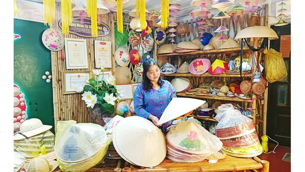 Chị Hương trong không gian trưng bày nón và giới thiệu về truyền thống làm nón làng Chuông.