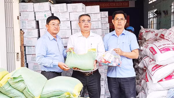 Nhà báo Lê Hoàng Triều (bên trái) trao quà hỗ trợ địa phương bị ảnh hưởng bởi mưa lũ.