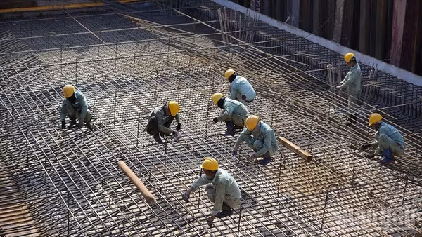 Công nhân duy trì nhịp độ làm việc khẩn trương trên công trường dưới thời tiết khắc nghiệt. (Ảnh: ÁNH DƯƠNG)