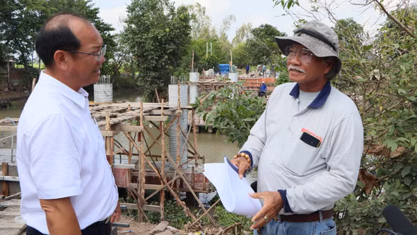 Lãnh đạo xã Châu Phú (bên trái) thăm hỏi đội xây cầu thiện nguyện.
