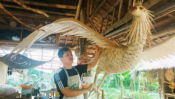 Anh Võ Tấn Tân bên tác phẩm chim phượng hoàng làm từ tre gai.