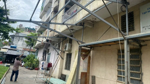 Công nhân tháo gỡ các khung sắt cơi nới tại cư xá Độc Lập sau vụ cháy. 