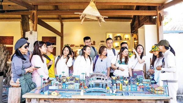 Du khách tìm hiểu nghệ thuật điêu khắc gỗ tại Làng Củi Lũ.